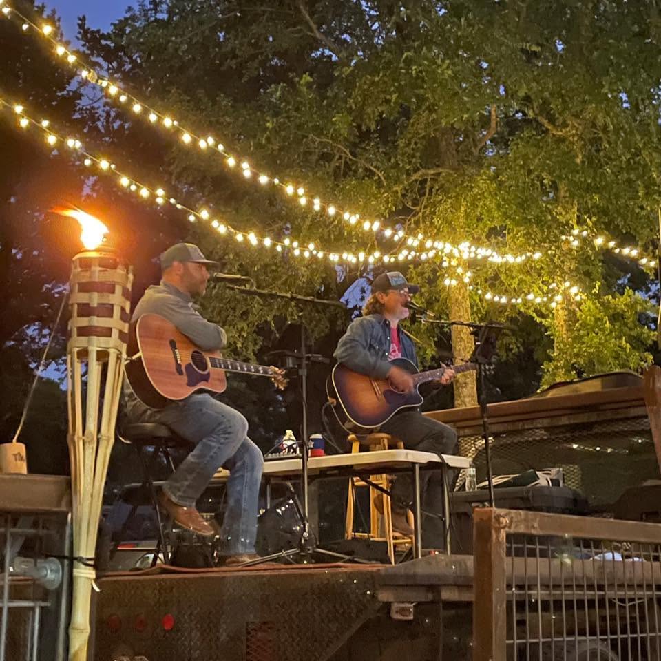 Lonestar Parish performing together beneath outdoor string lights